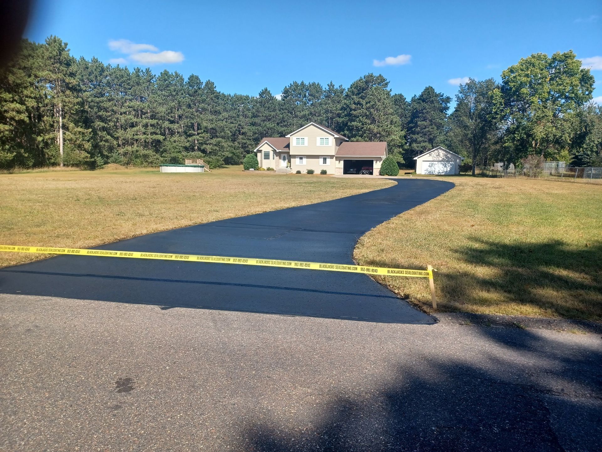 A driveway leading to a house in the middle of a field.
