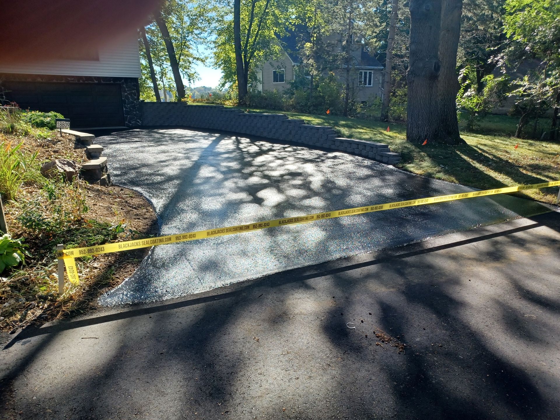 A driveway with a yellow tape around it and a house in the background.