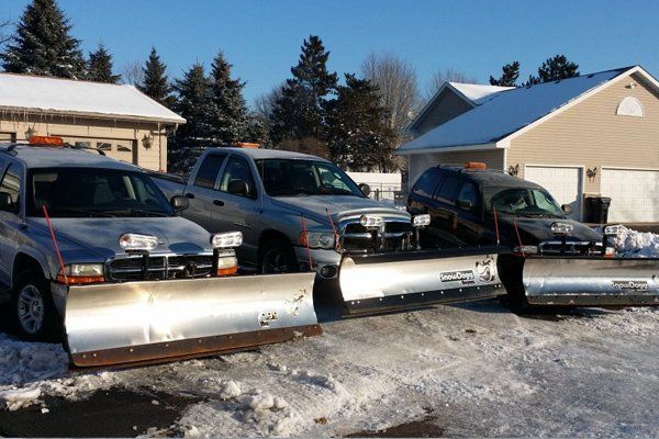 A row of snow plows are parked in front of a house