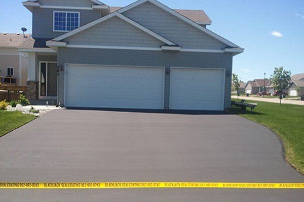 A gray house with a white garage door and a concrete driveway