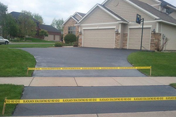 A driveway with a yellow caution tape around it and a house in the background