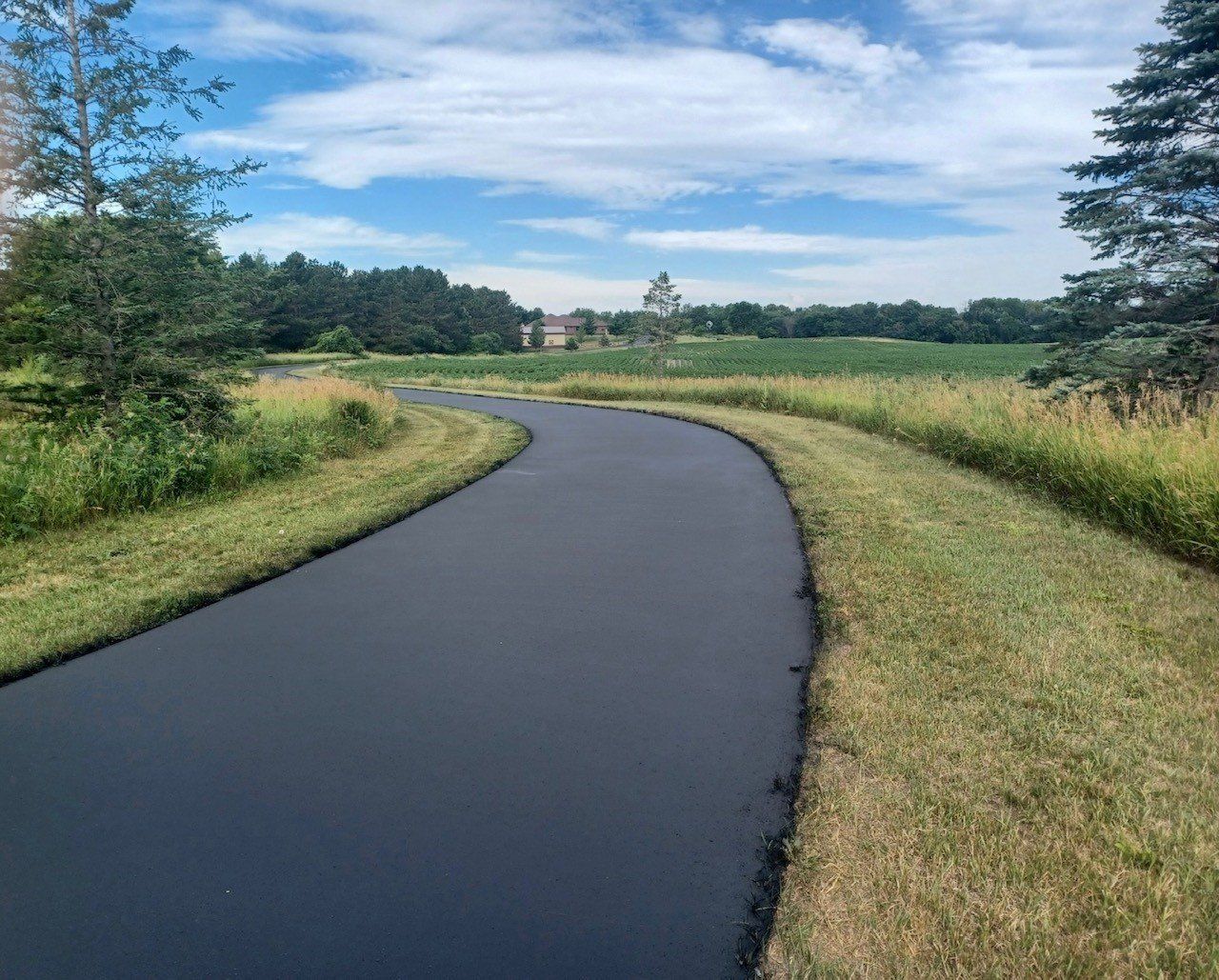 A curvy road going through a grassy field on a sunny day.