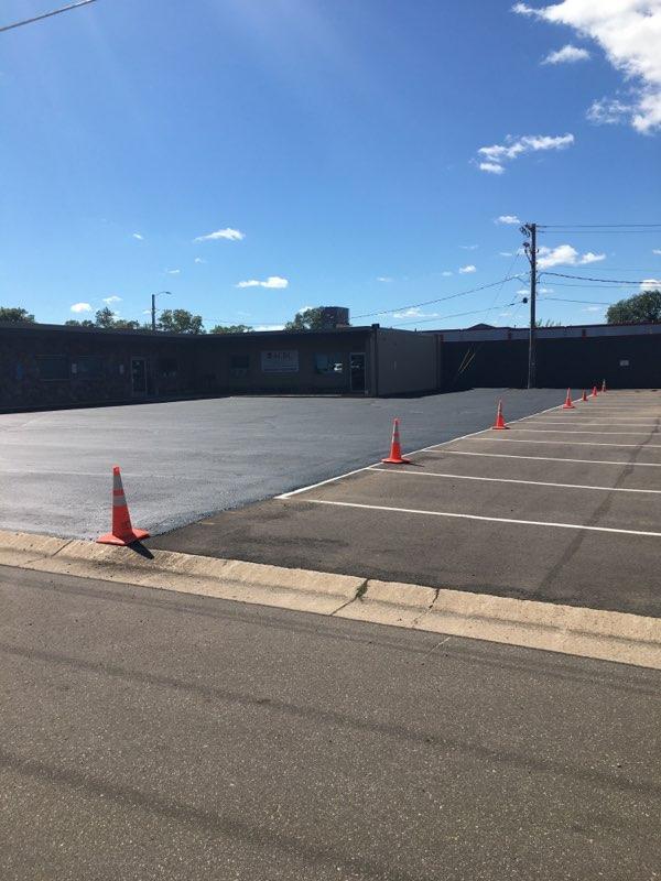 A parking lot with orange cones and a building in the background.