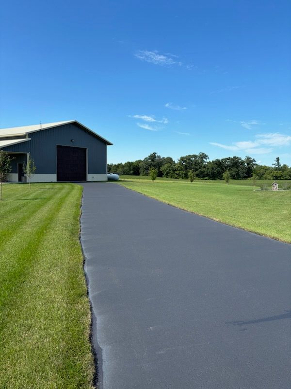 A driveway leading to a barn with a blue sky in the background
