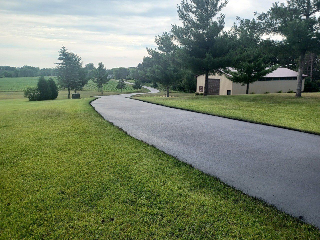 A driveway that is surrounded by grass and trees