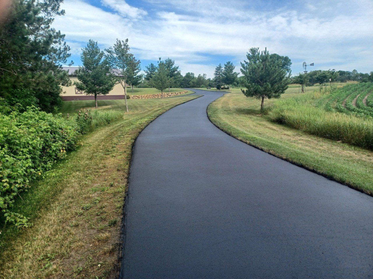 A driveway that is surrounded by grass and trees