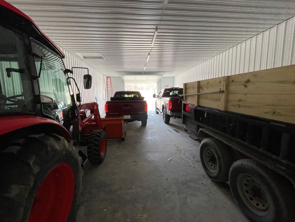 Tractors and farm trailers parked inside a large covered shed