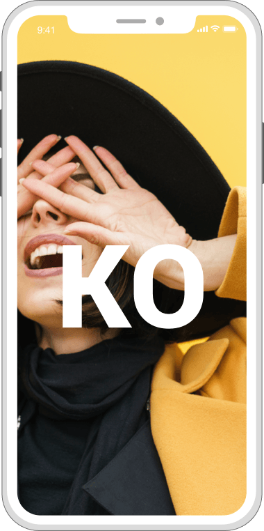 Phone displaying a woman covering her face with hands, wearing a black hat and coat, with the letters