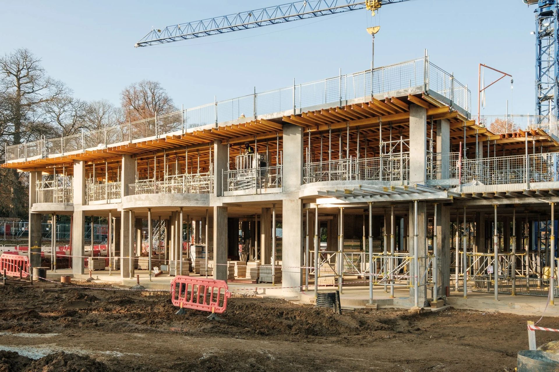 Two workers in orange vests and hard hats on a platform overlook a busy cargo port at night.