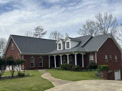 A large brick house with a gray roof and white trim.