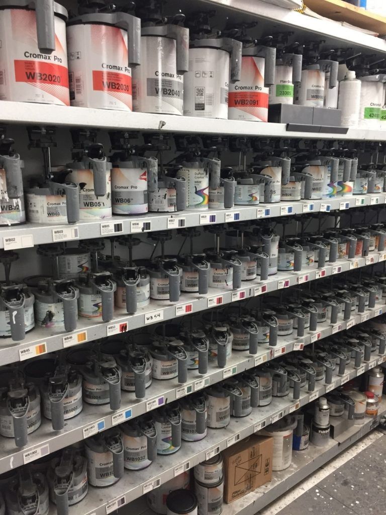 A shelf filled with lots of containers of paint.