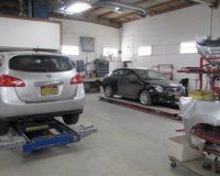 Two cars are sitting on a lift in a garage.