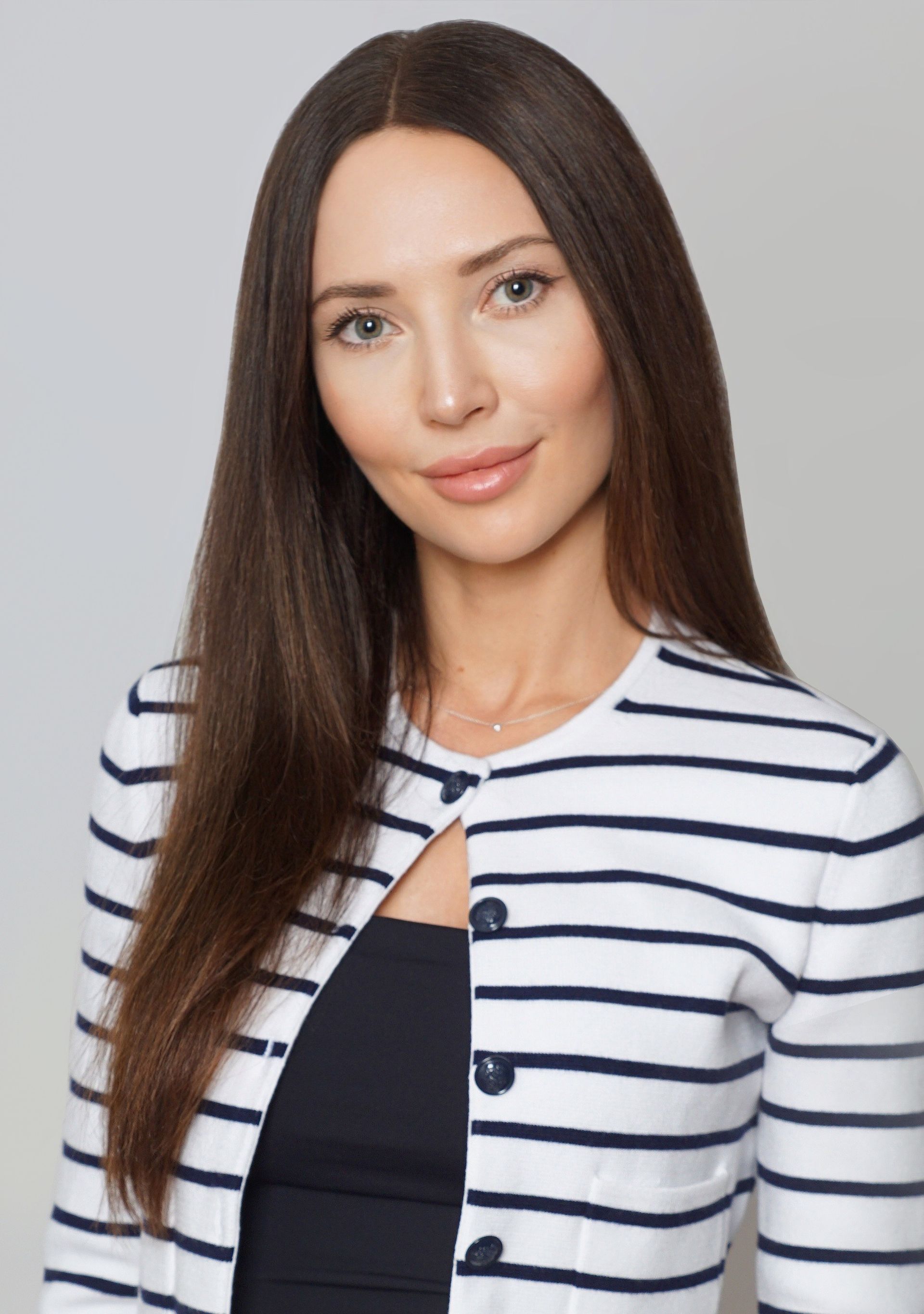 Woman with long dark hair wearing a striped jacket, smiling at the camera.