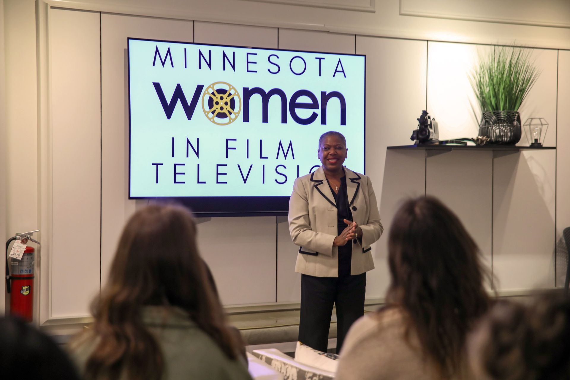 A woman is standing in front of a screen that says minnesota women in film television.