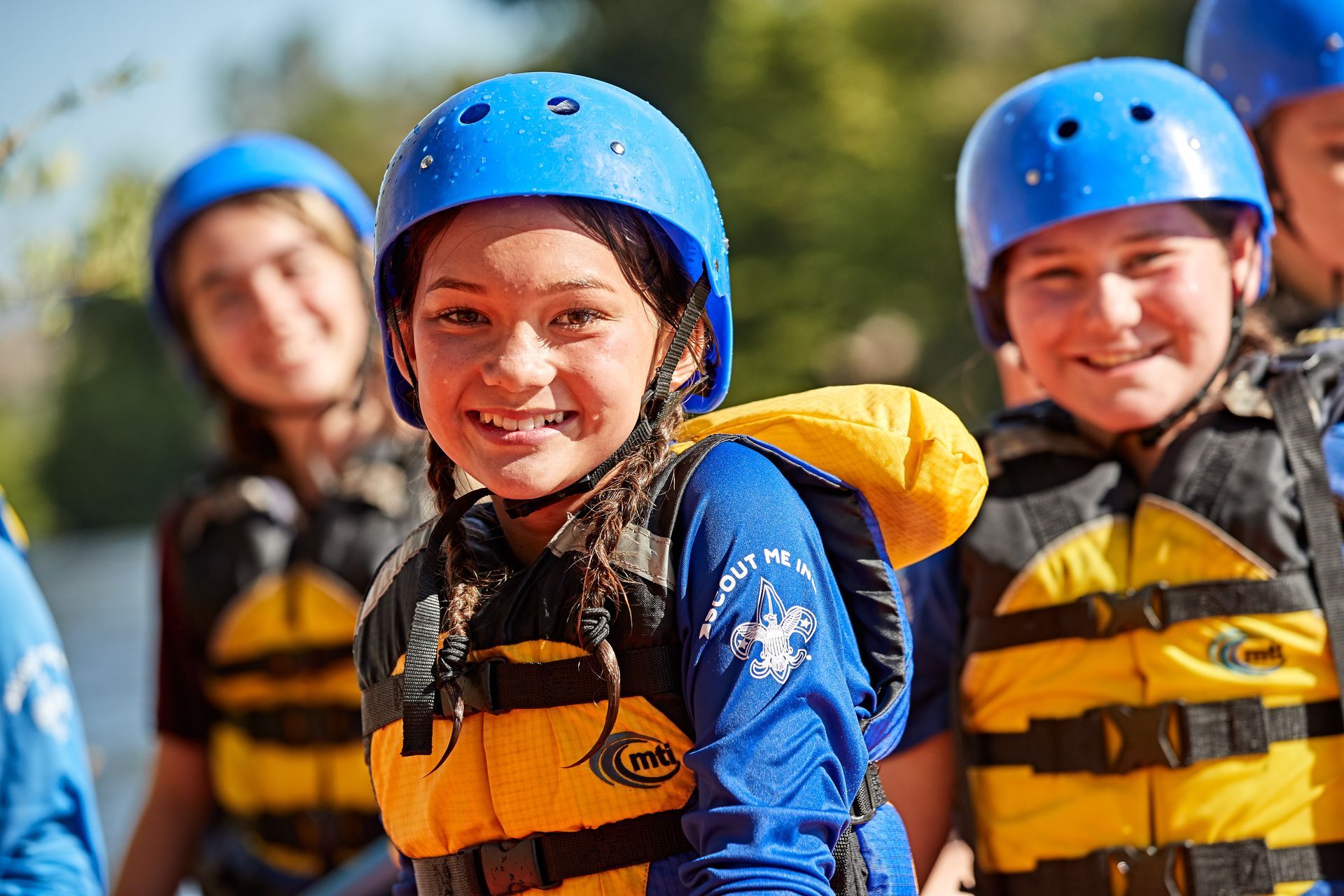 A group of children wearing life jackets and helmets are standing next to each other.