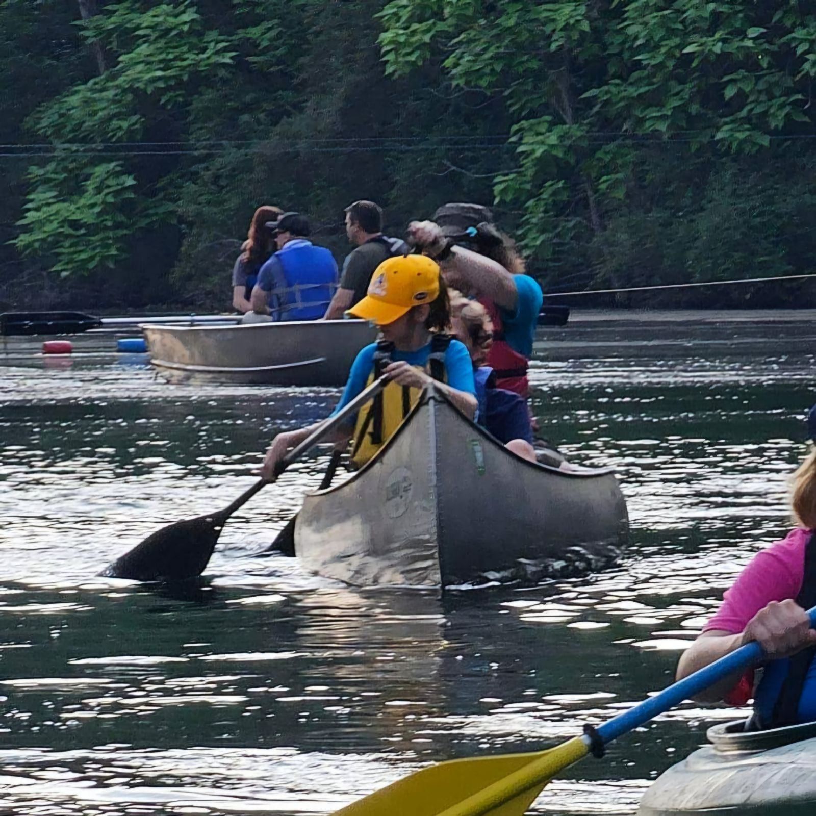 A woman in a life jacket is holding a raft in the air.