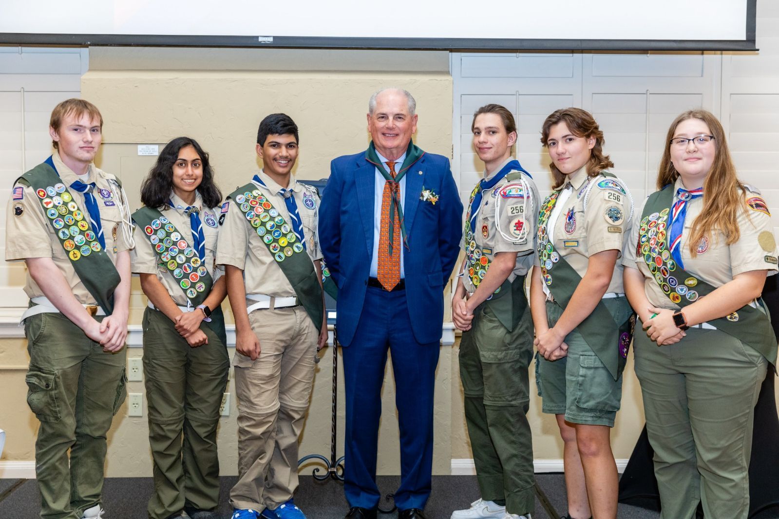 A group of boy scouts are posing for a picture with a man in a suit and tie.