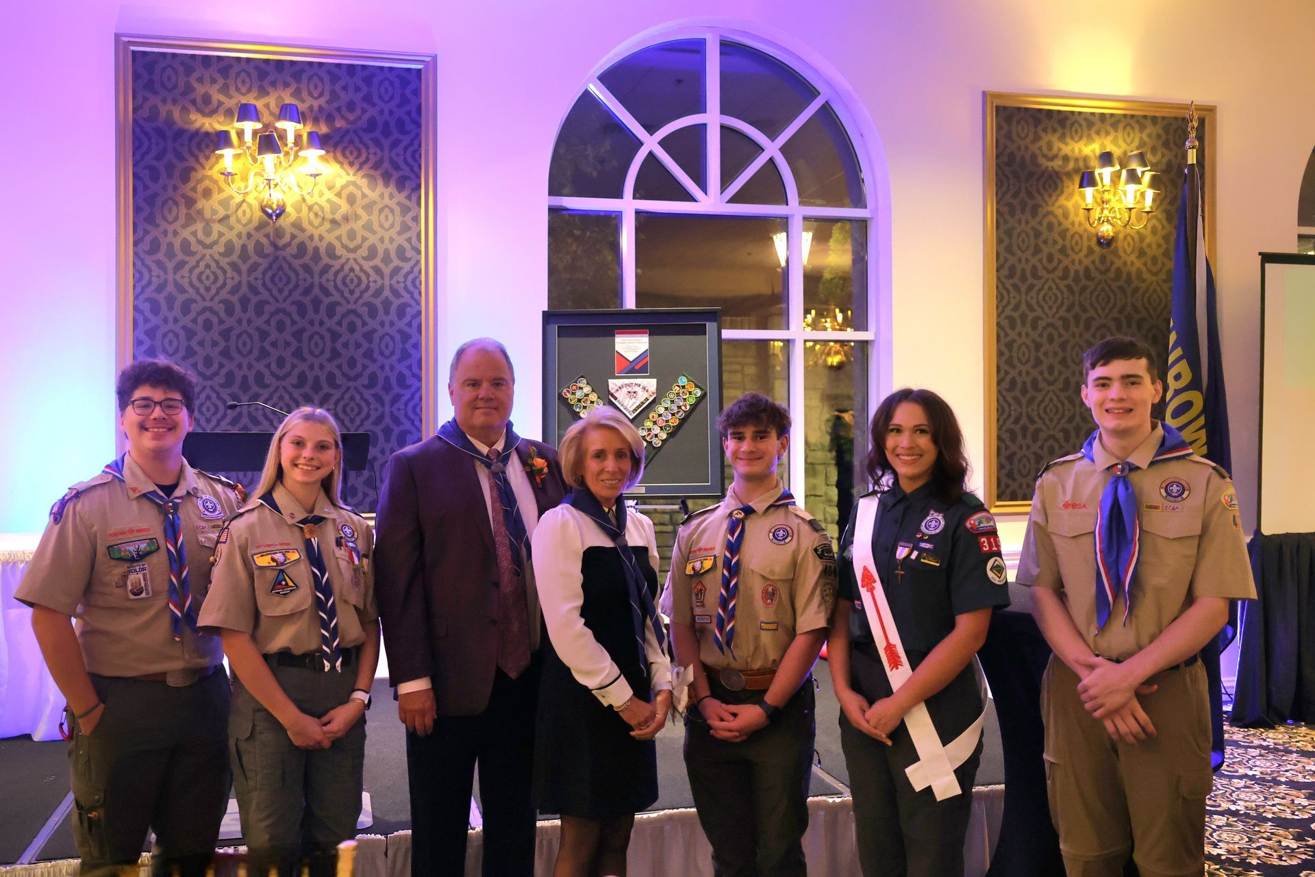 A group of boy scouts are posing for a picture with a man in a suit and tie.
