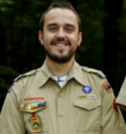 Man in Boy Scout uniform smiling outdoors.