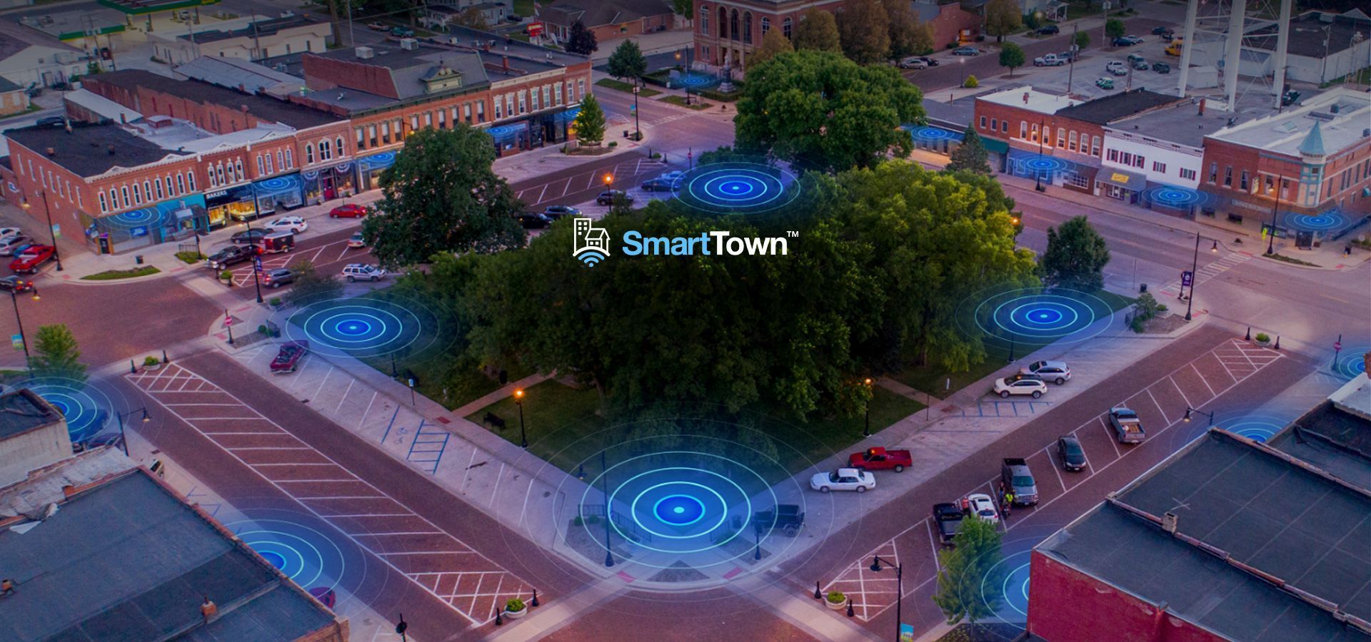 An aerial view of a city at night with a smart town logo in the middle of the street.