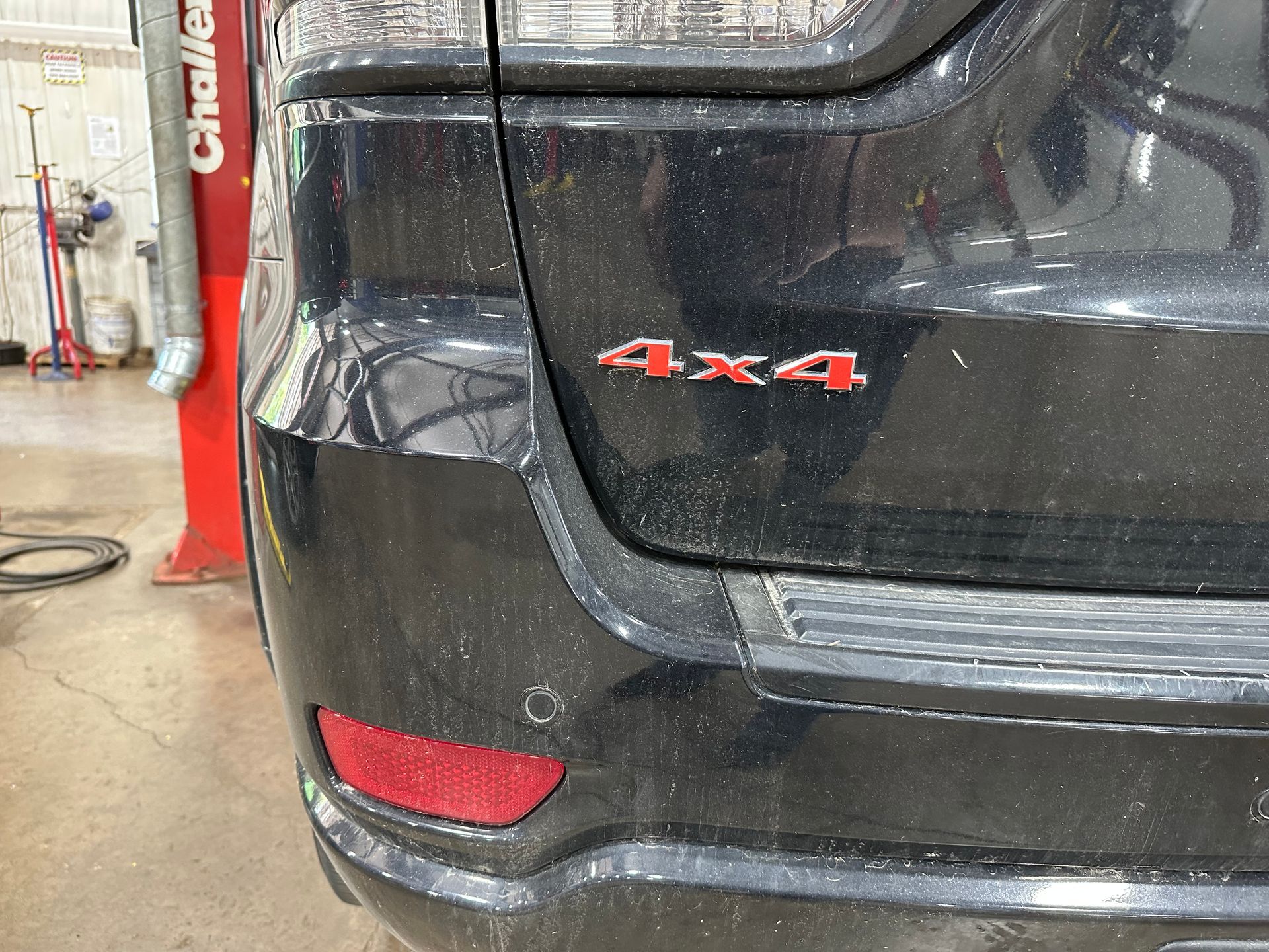 A black jeep grand cherokee is parked in a garage. | Lou's Car Care Center Inc.