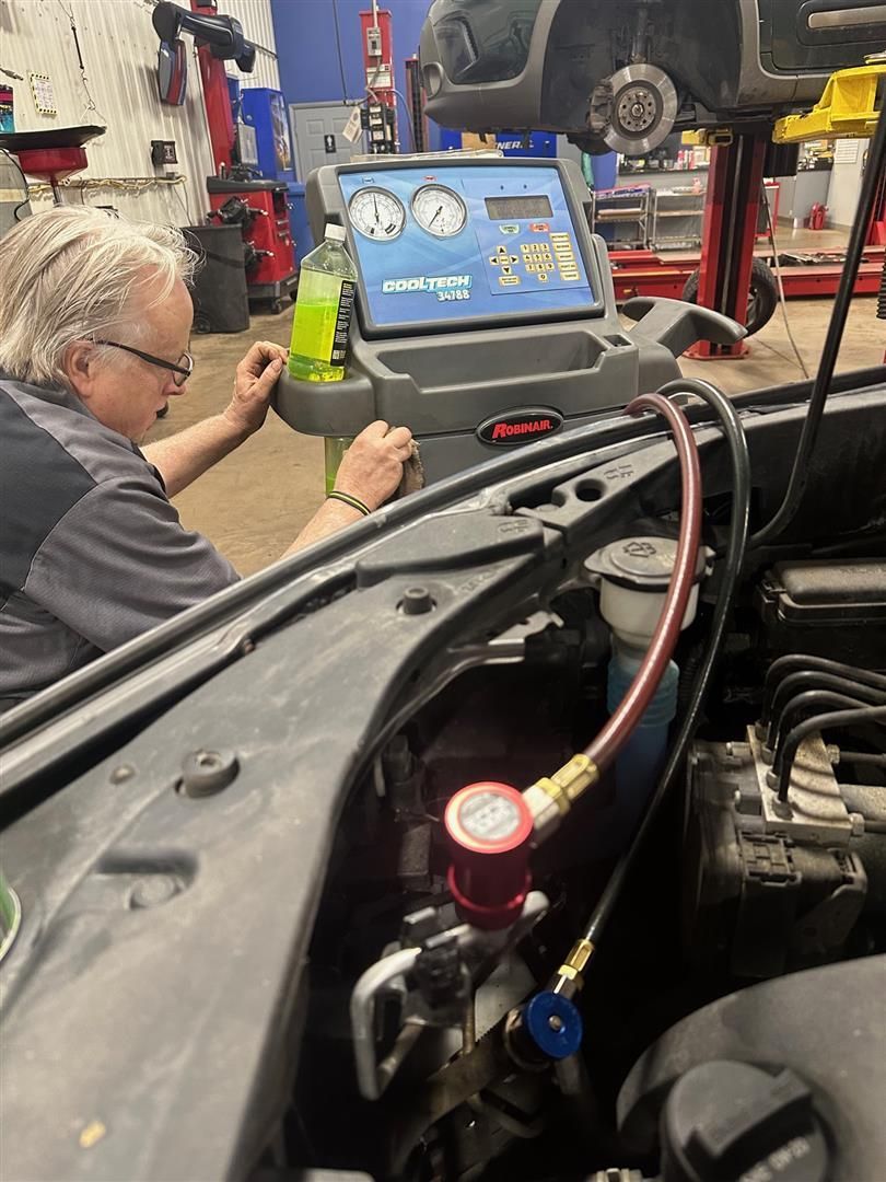 A man is working on a car in a garage.  | Lou's Car Care Center, Inc.