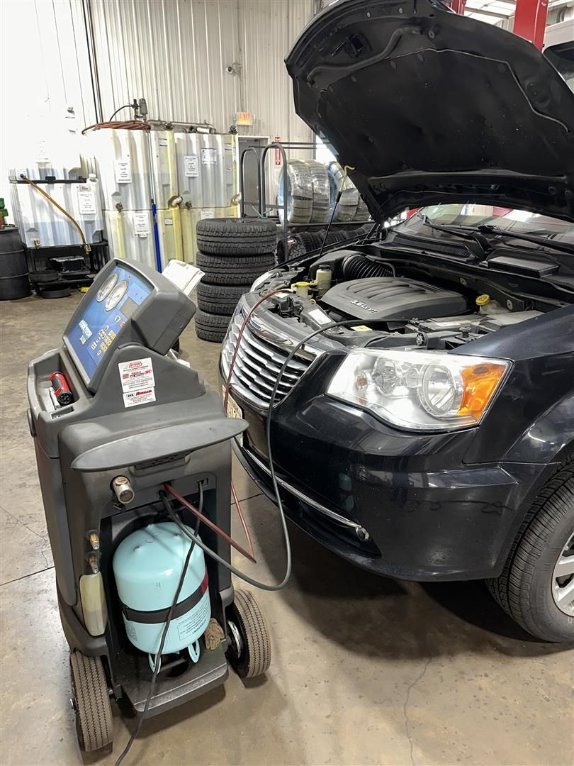 A car is being serviced in a garage with the hood open. | Lou's Car Care Center, Inc.