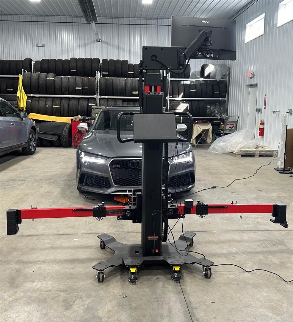 A car is parked in a garage next to a machine. | Lou's Car Care Center, Inc.