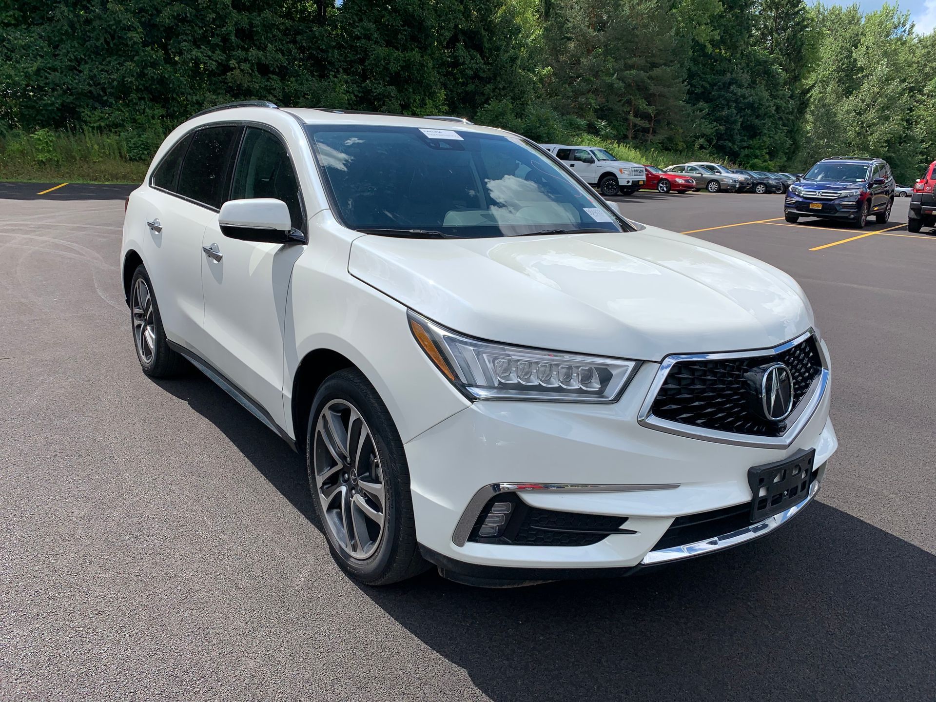 A white acura mdx is parked in a parking lot. | Lou's Car Care Center, Inc.