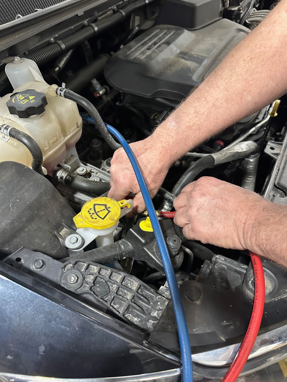 Auto AC Recharge Hoses Being Attached To Vehicle By Technician | Lou's Car Care Center, Inc.