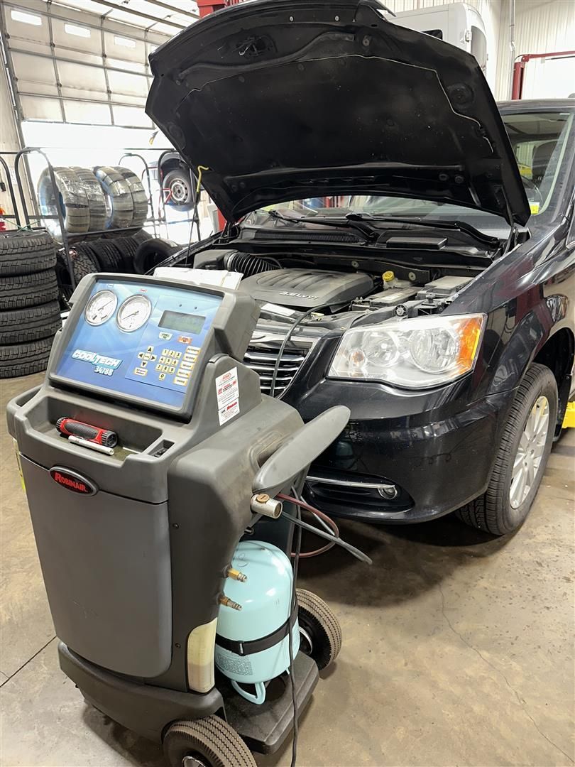 A car is being serviced in a garage with the hood open. | Lou's Car Care Center