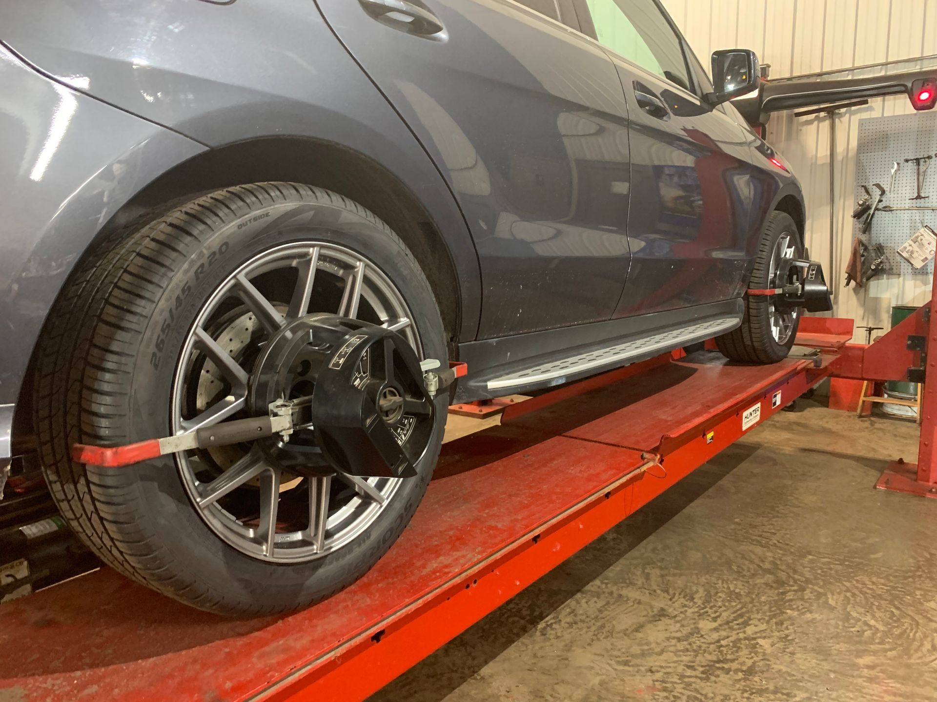 A car is being aligned on a lift in a garage. | Lou's Car Care Center Inc.