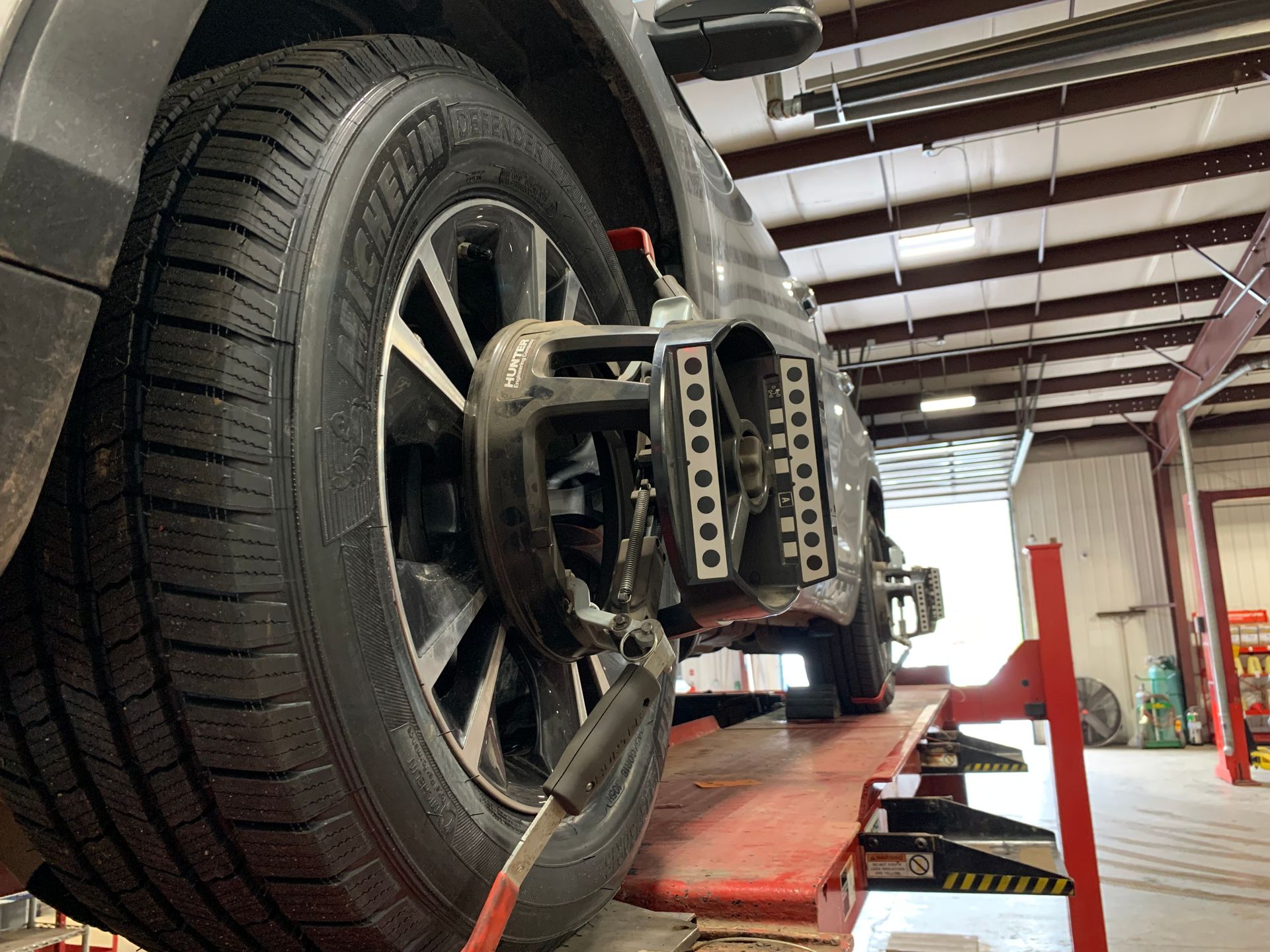 A car is being adjusted on a lift in a garage. | Lou's Car Care Center, Inc.