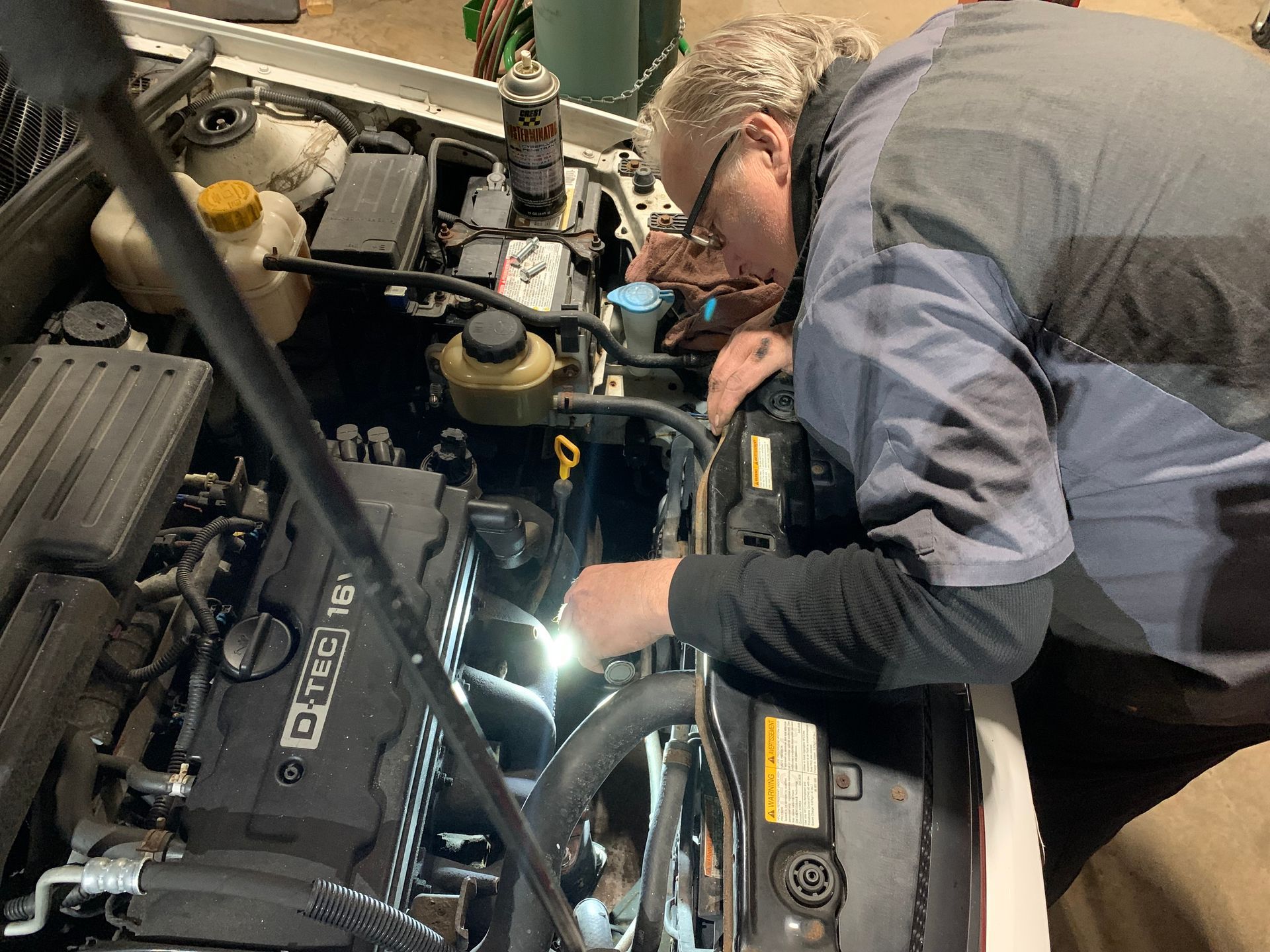 A man is working on the engine of a car. | Lou's Car Care Center, Inc.