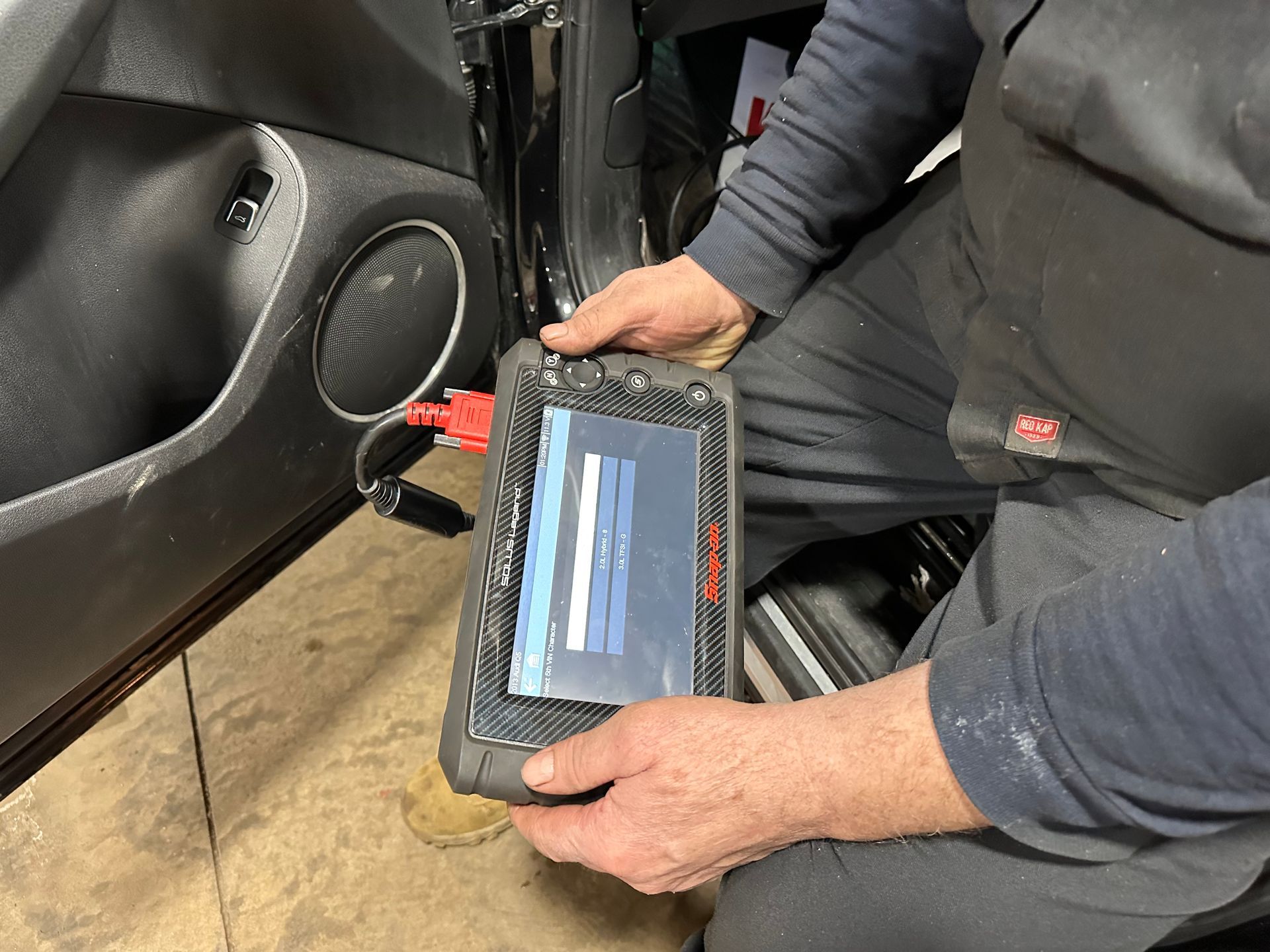 A man is using a tablet in a car. | Lou's Car Care Center, Inc.