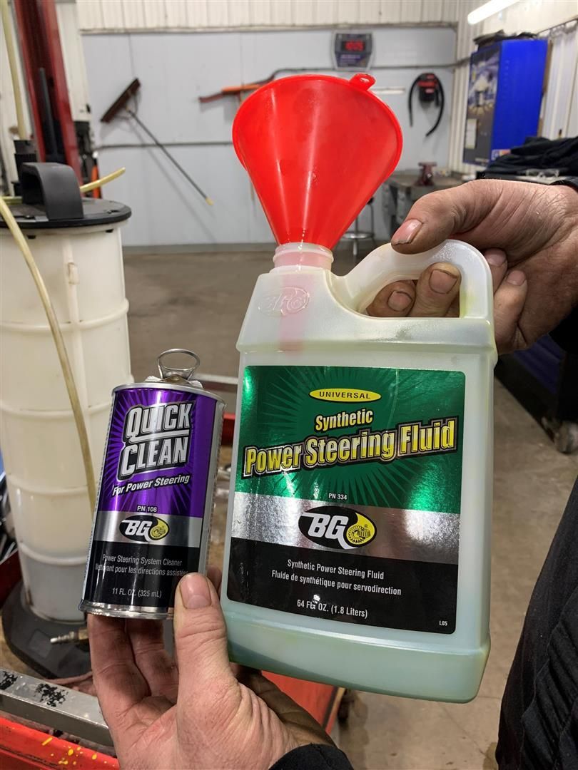 A person is holding a bottle of power steering fluid  | Lou's Car Care Center Inc.