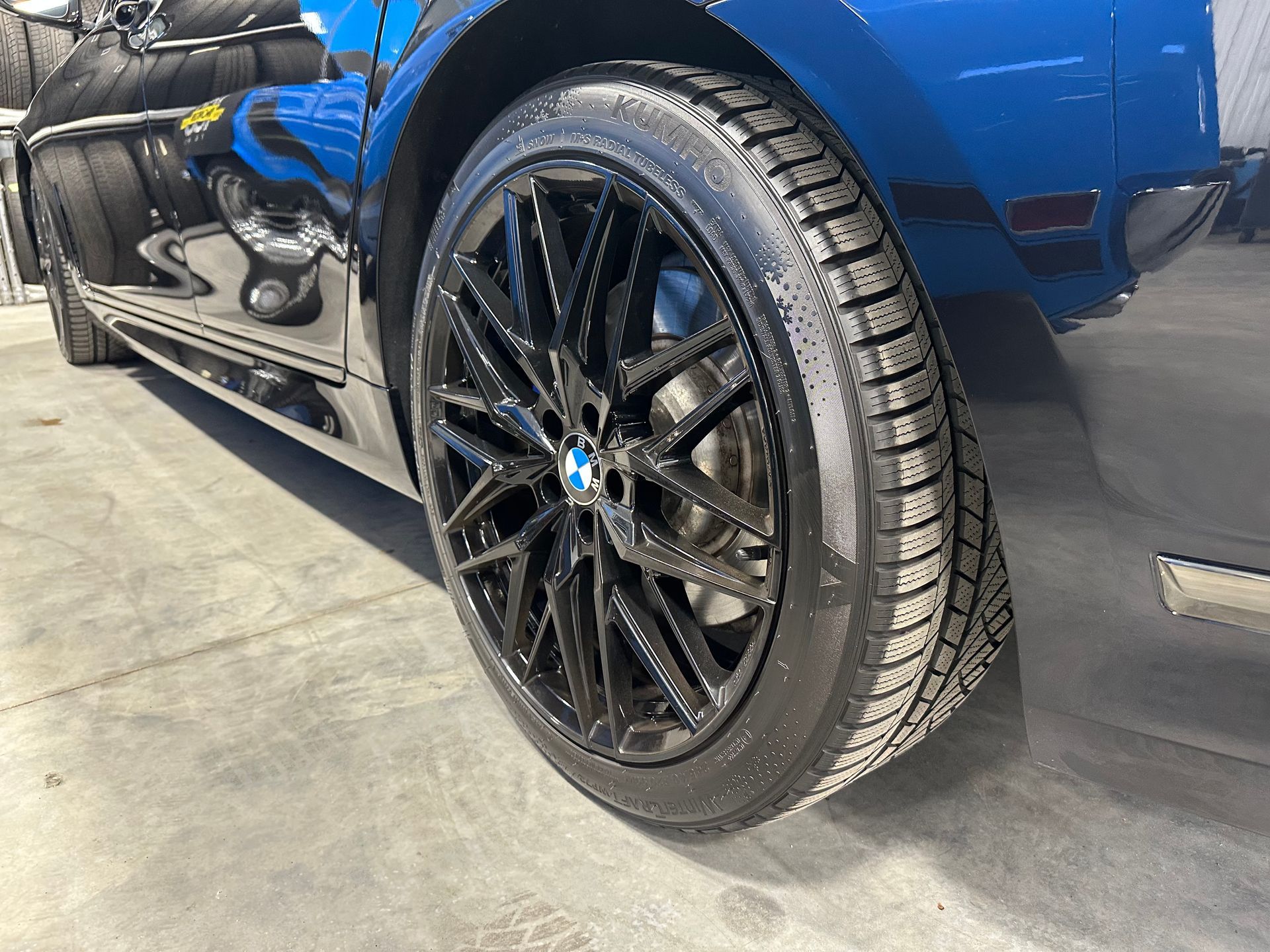 A blue bmw with black wheels and tires is parked in a garage. | Lou's Car Care Center Inc.