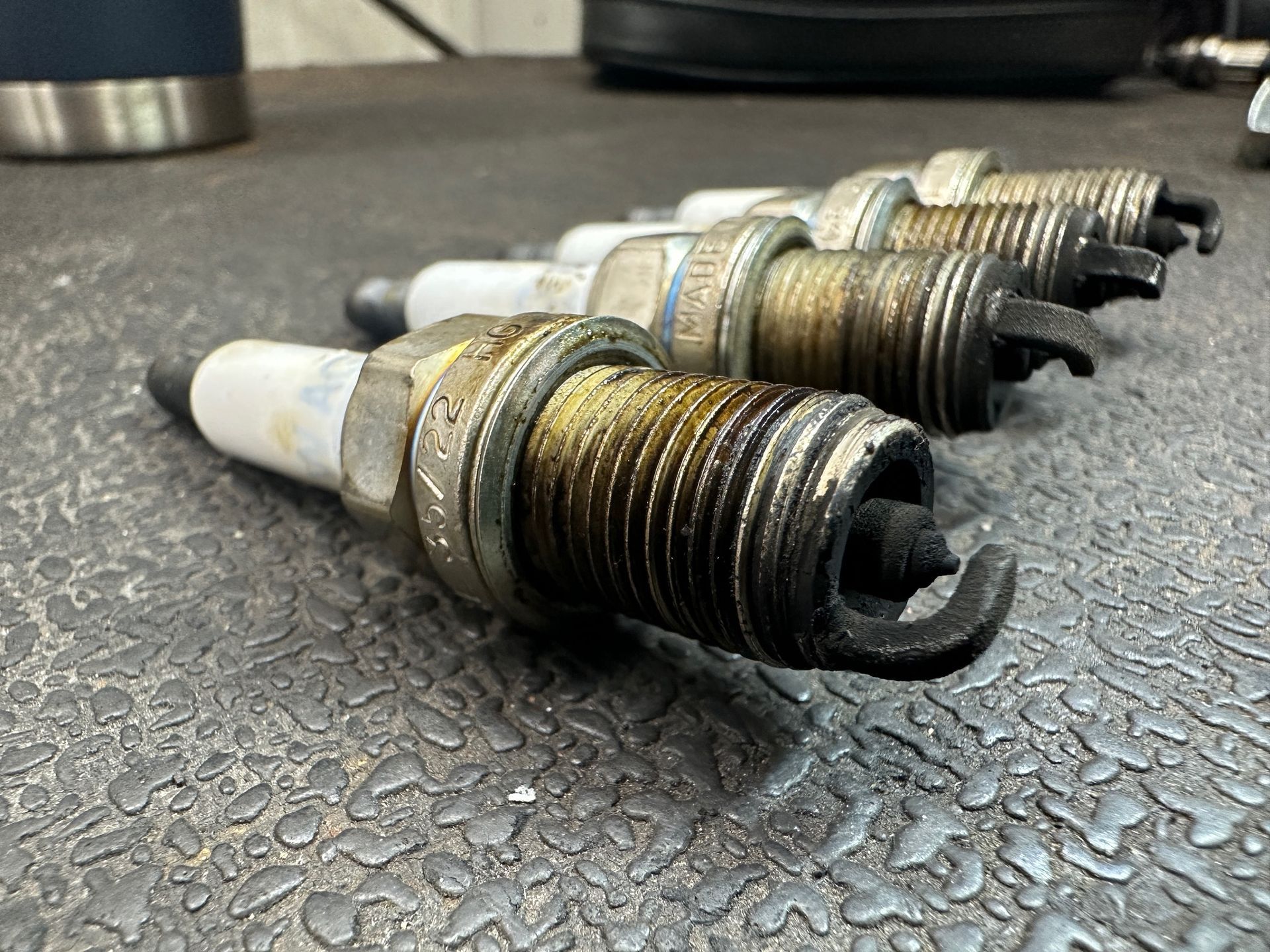 A bunch of spark plugs are sitting on a table. | Lou's Car Care Center, Inc.