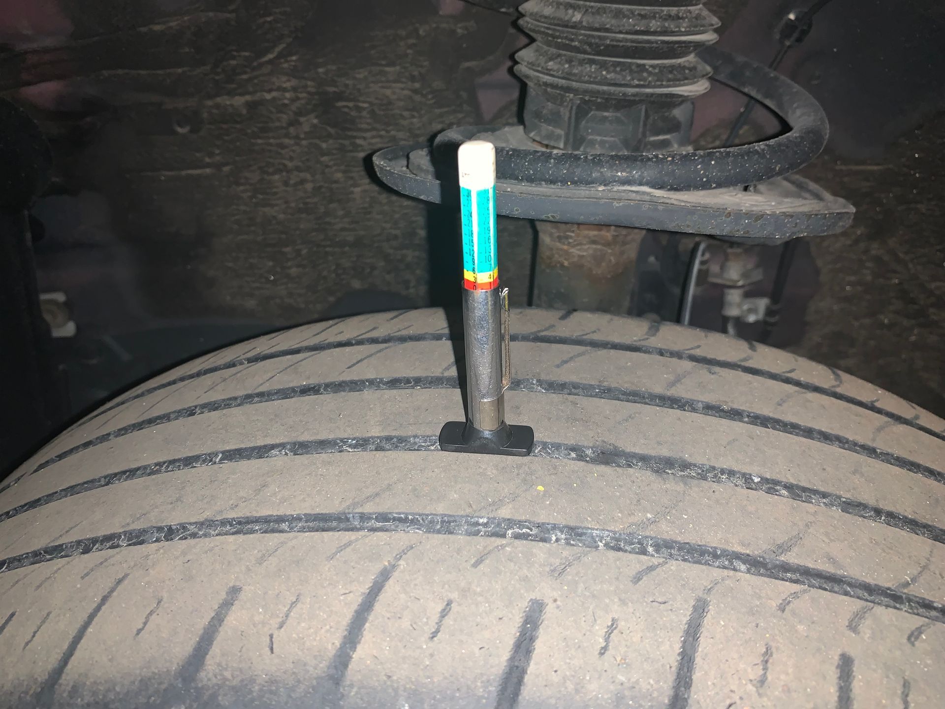 A tire with a tire gauge sticking out of it | Lou's Car Care Center Inc.