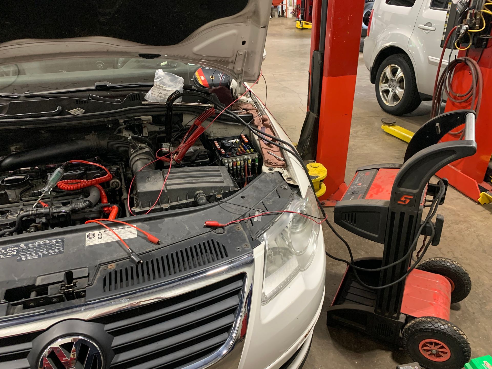 A car is being worked on in a garage with the hood open. | Lou's Car Care Center, Inc.