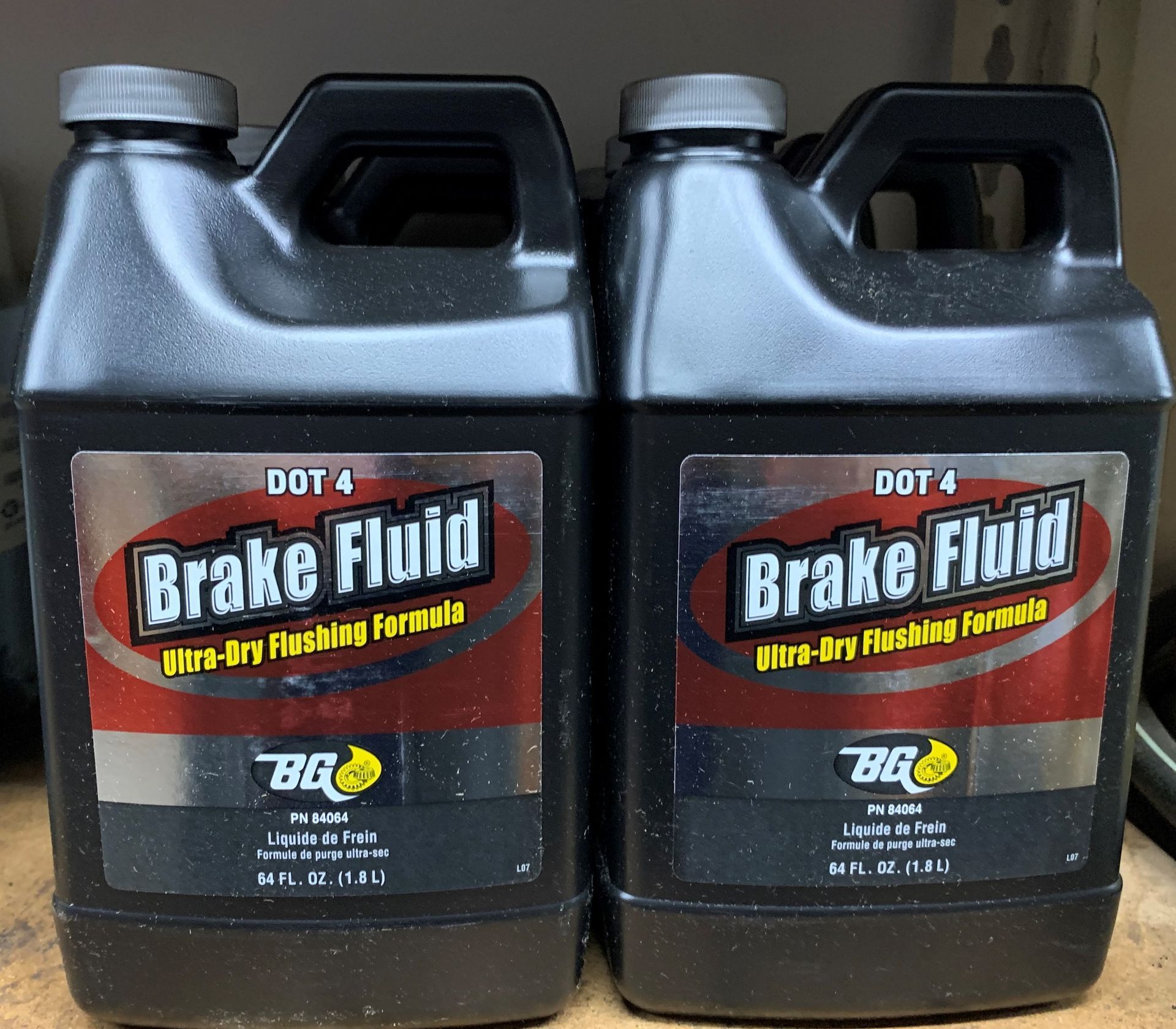 Two gallons of brake fluid sit on a wooden table  | Lou's Car Care Center Inc.