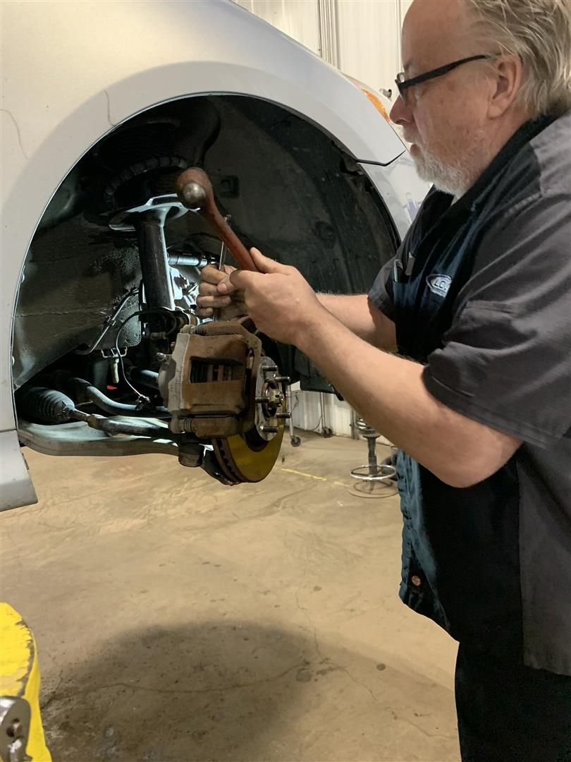 A man is working on a car in a garage. | Lou's Car Care Center Inc.