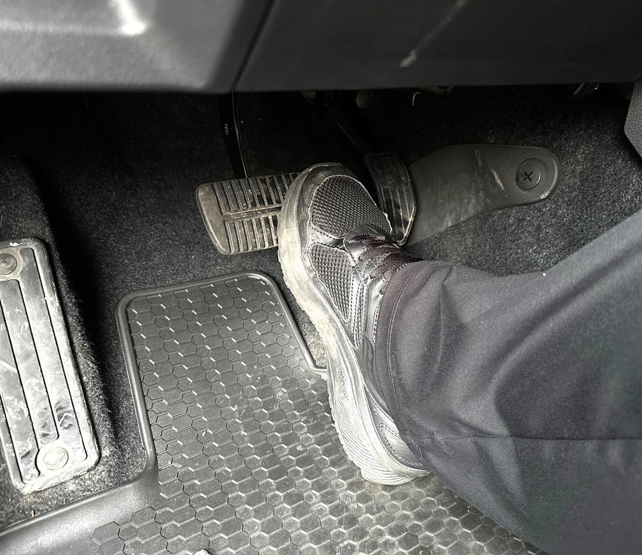 A person is pressing the brake pedal in a car. | Lou's Car Care Center