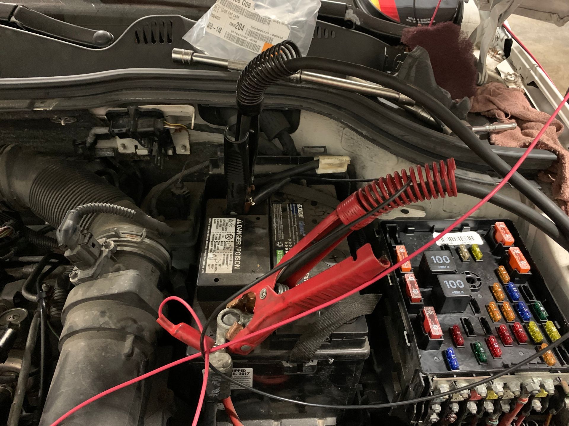 A car battery is being charged with a jump starter. | Lou's Car Care Center Inc.