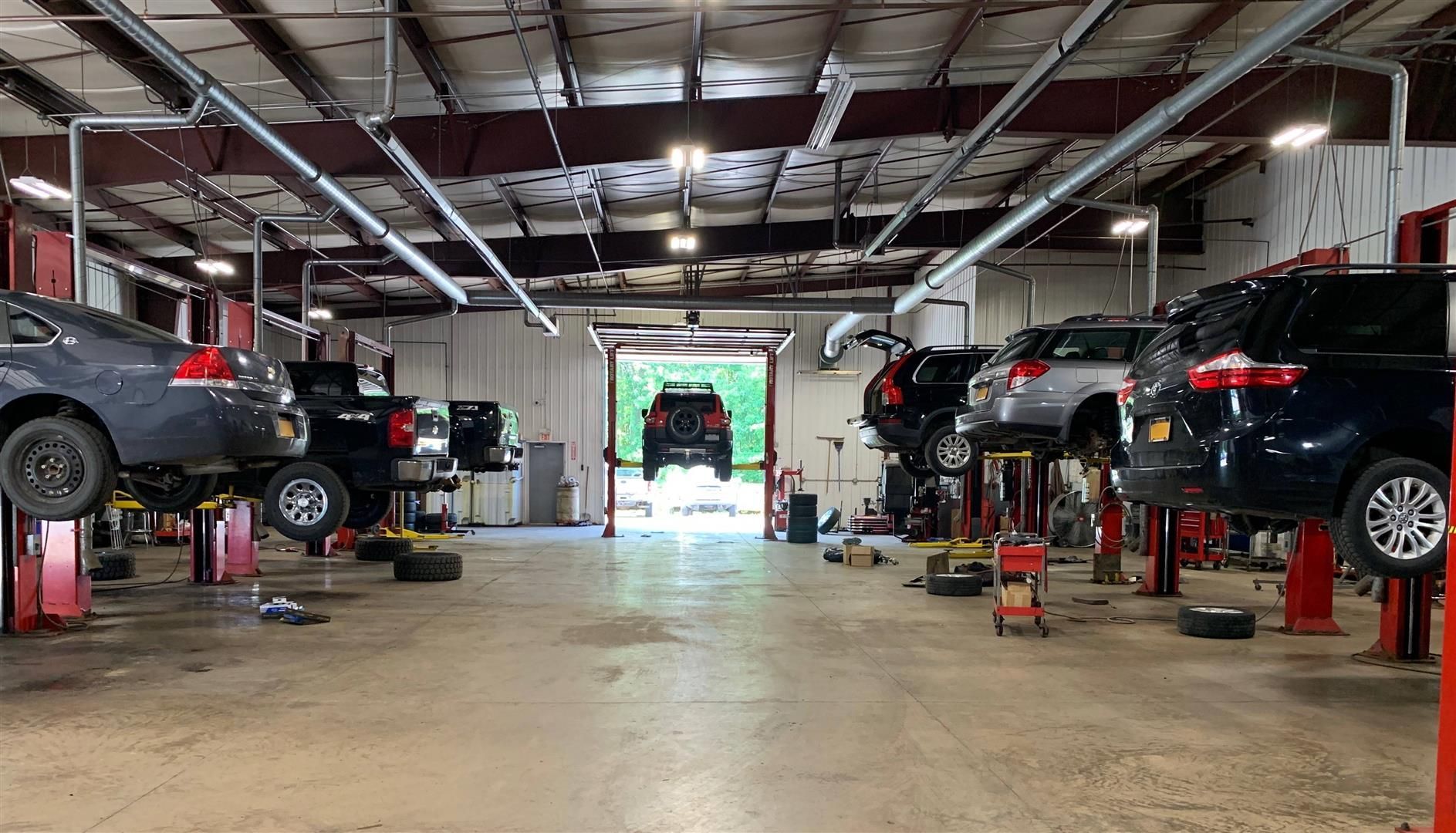 A row of cars are sitting on lifts in a garage. | Lou's Car Care Center