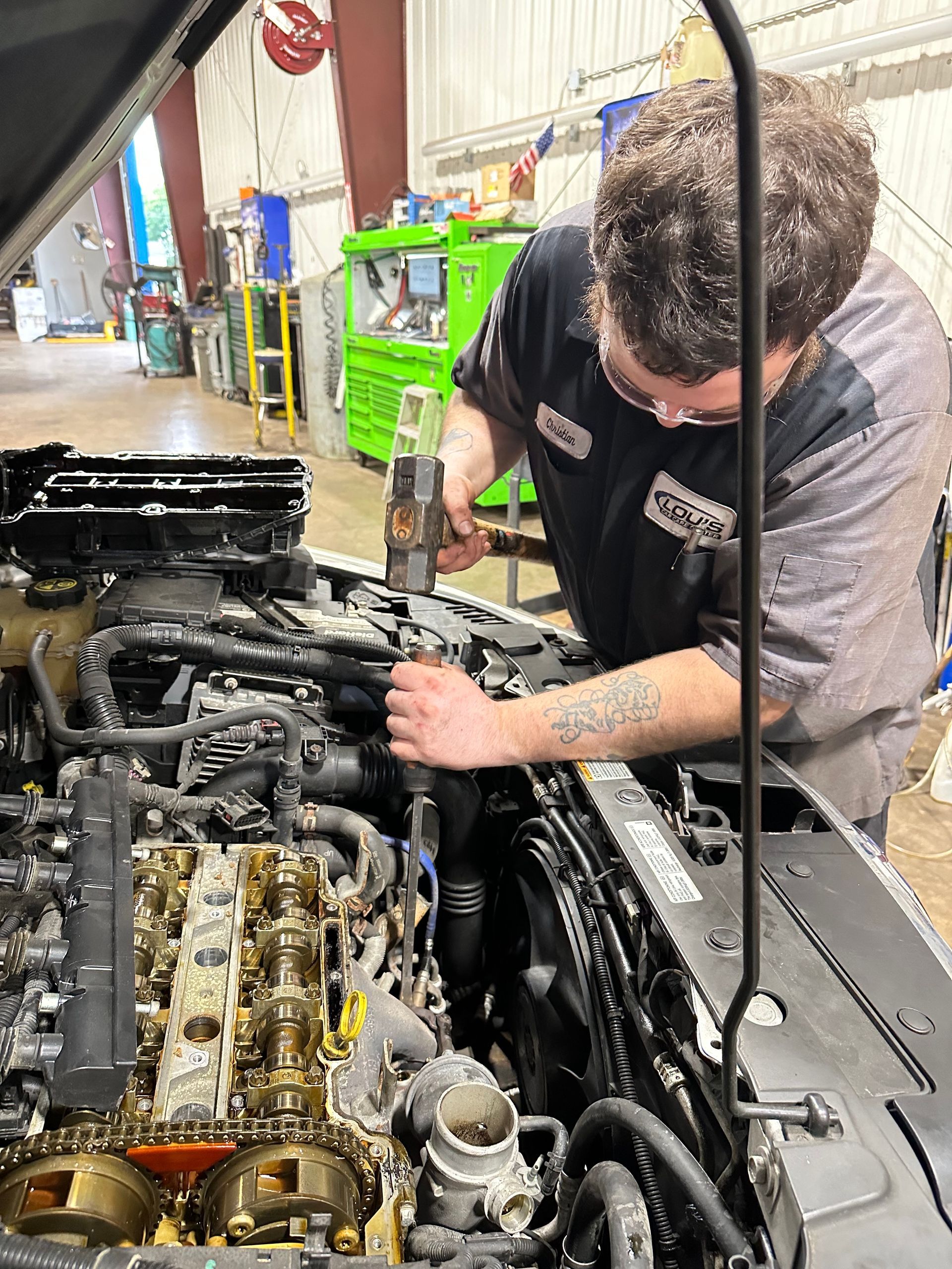 Mechanic using tools to break a bolt loose on vehicle engine in the auto repair shop.