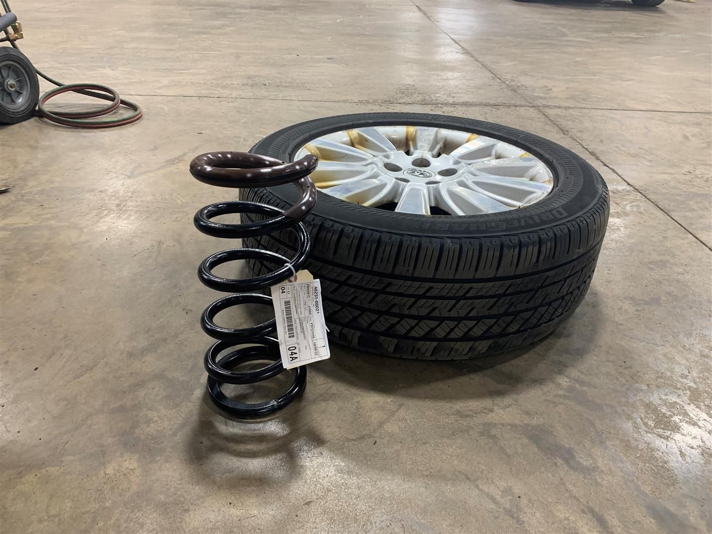 A tire and spring are sitting on a concrete floor. | Lou's Car Care Center Inc.