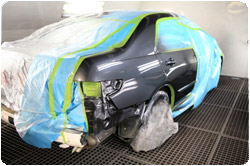 A car is being painted in a paint booth. | Lou's Car Care Center