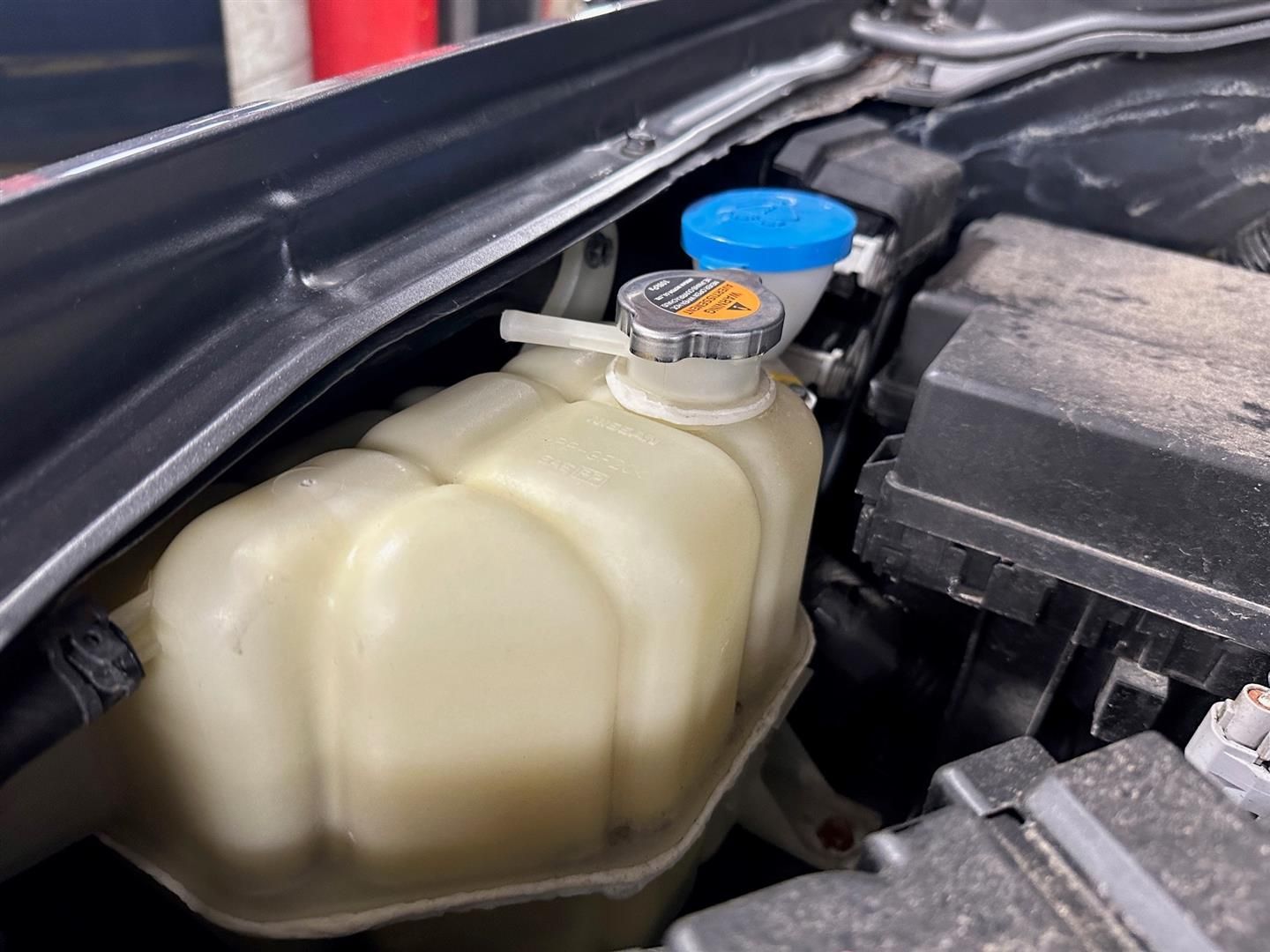 A close up of a coolant reservoir under the hood of a car. | Lou's Car Care Center, Inc.