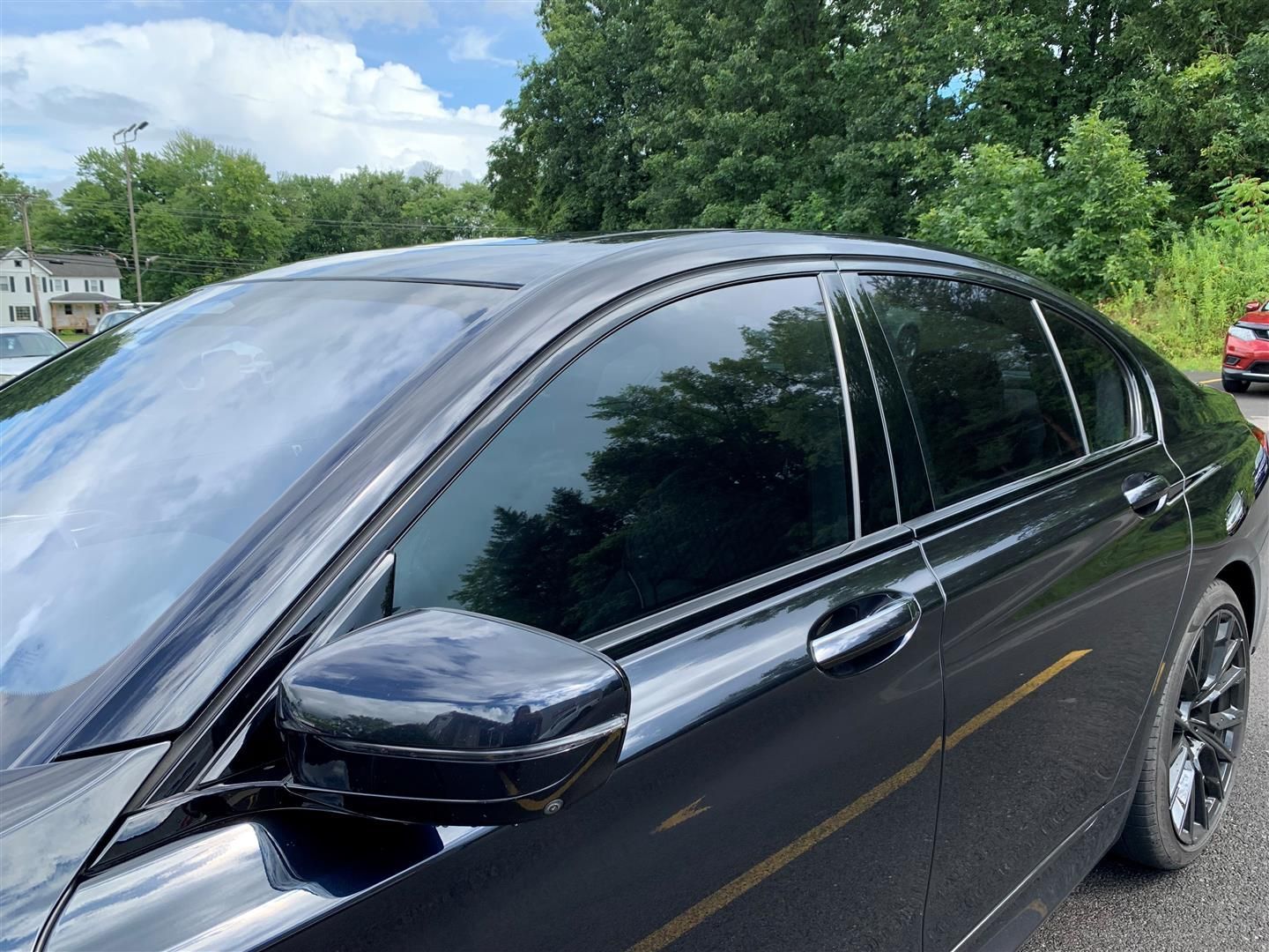 A black car with tinted windows is parked on the side of the road. | Lou's Car Care Center, Inc.